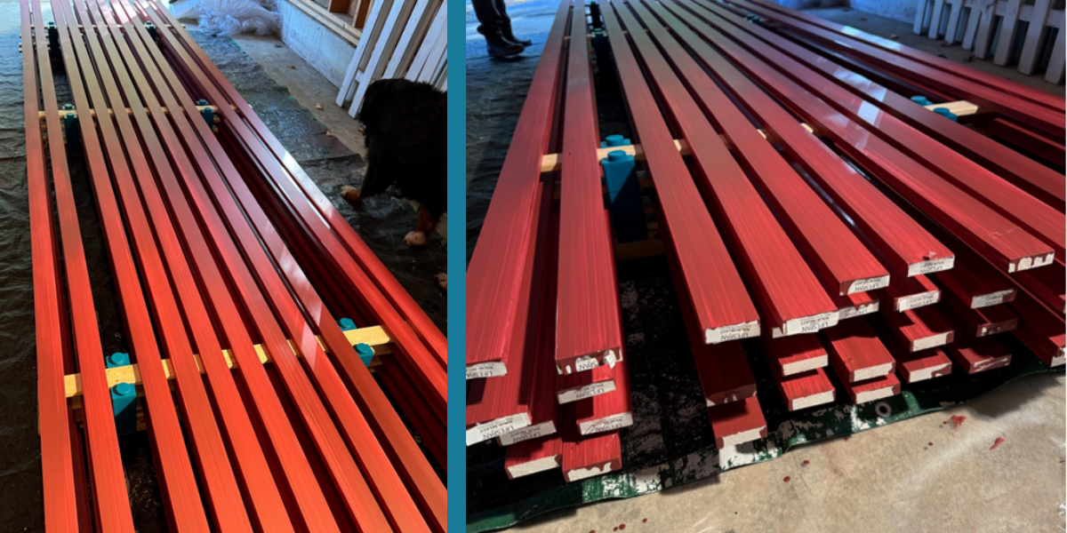 Deep red gloss 5/4 trim drying in stacked layers on PaintBlox Pro supports