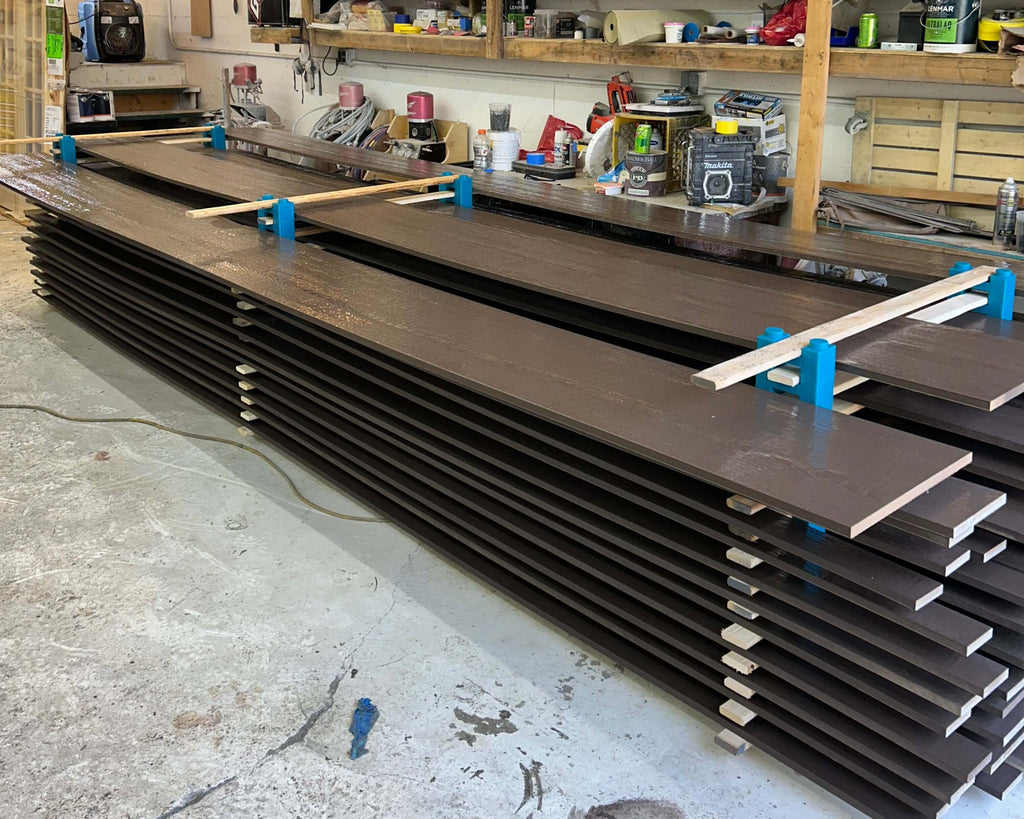 A large-scale professional drying rack built with PaintBlox Pro Shop 96 blocks, stacking long, freshly painted boards in a workshop.