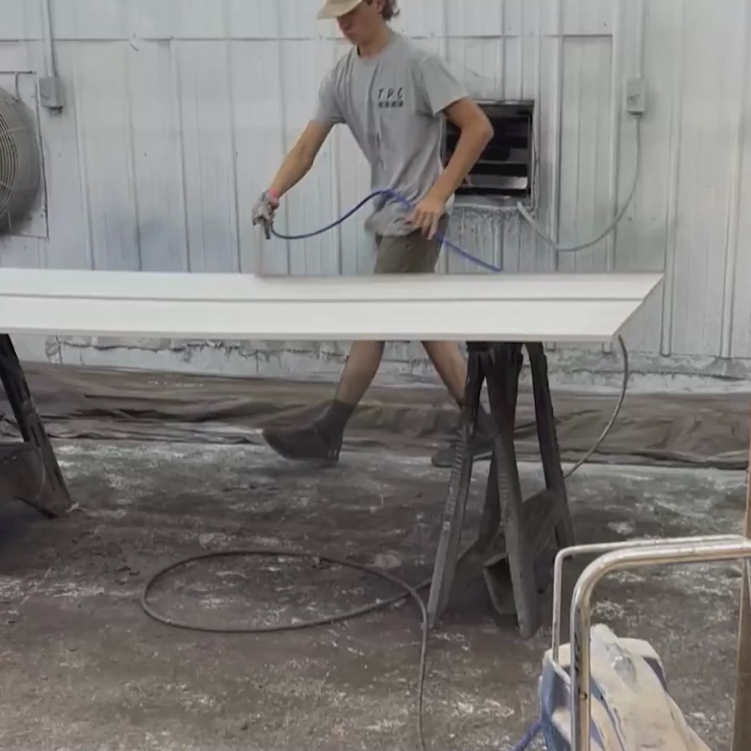 video of man painting planks with spray gun and stacking them to dry.